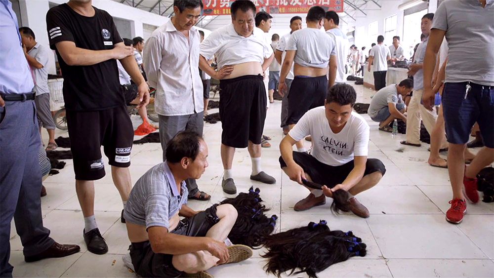 A group of men seated around bundles of hair at a market for hair collectors.