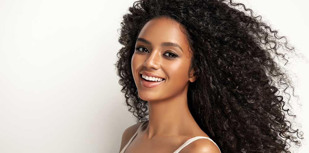 Image of a black woman with steam-styled curly hair extensions, challenging the misconception of virgin hair labels.