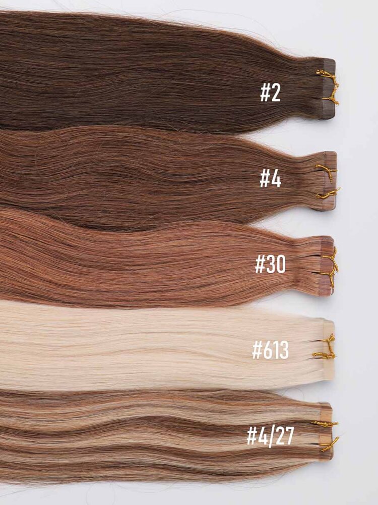 Close-up of tape tops on colored straight tape-in extensions with visible shade differences.