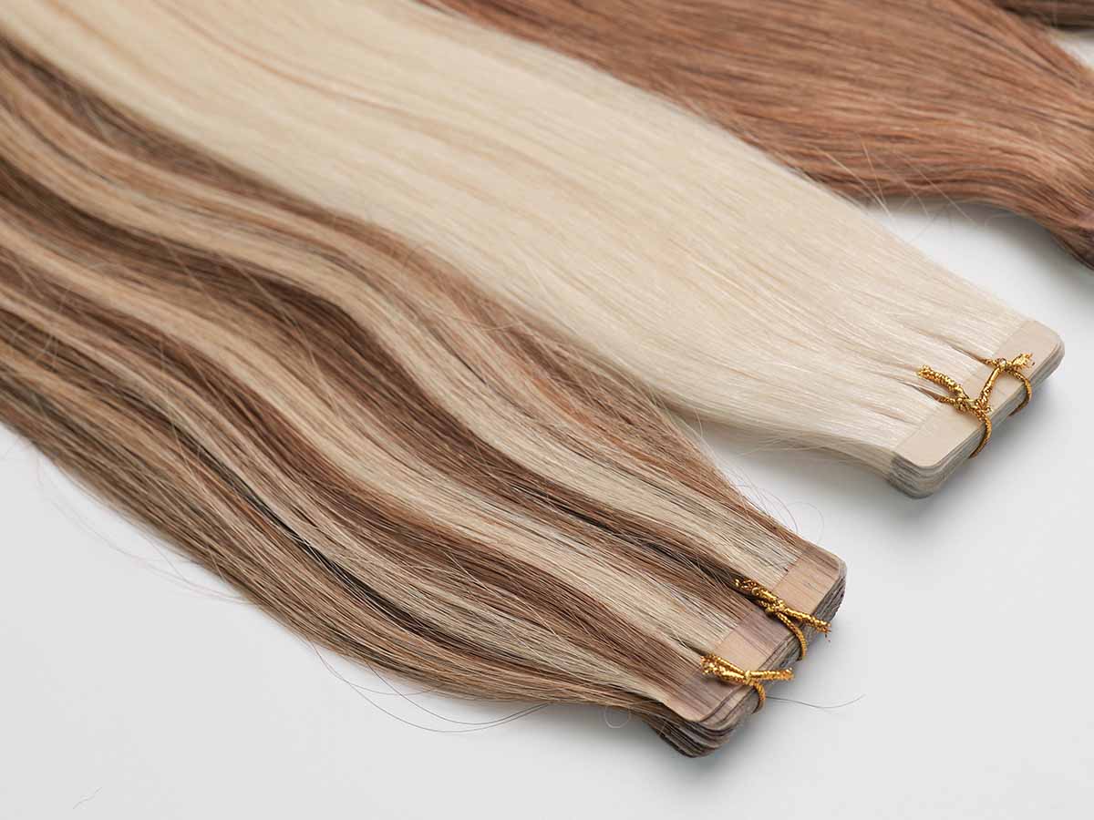 Close-up of straight tape-in extensions in shades 613 and P4/27, focusing on color detail and tape area.