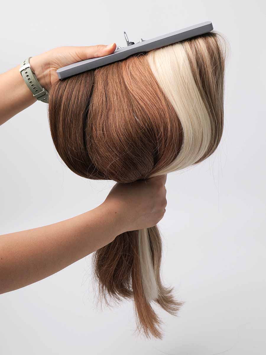 Bundle of colored straight tape-in extensions held in a curved shape, displaying multiple color tones.