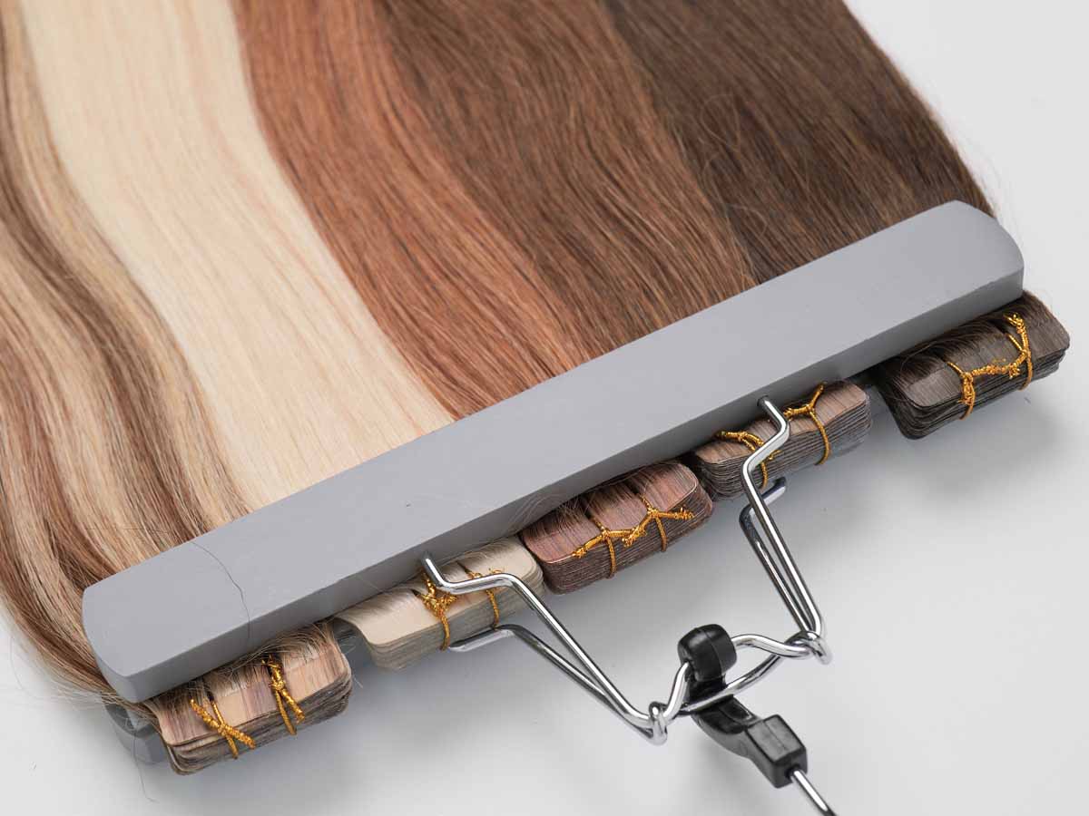 Five colored straight tape-in extensions on a hanger, with tape sections facing the camera in shades 2, 4, 30, 613, and P4/27.