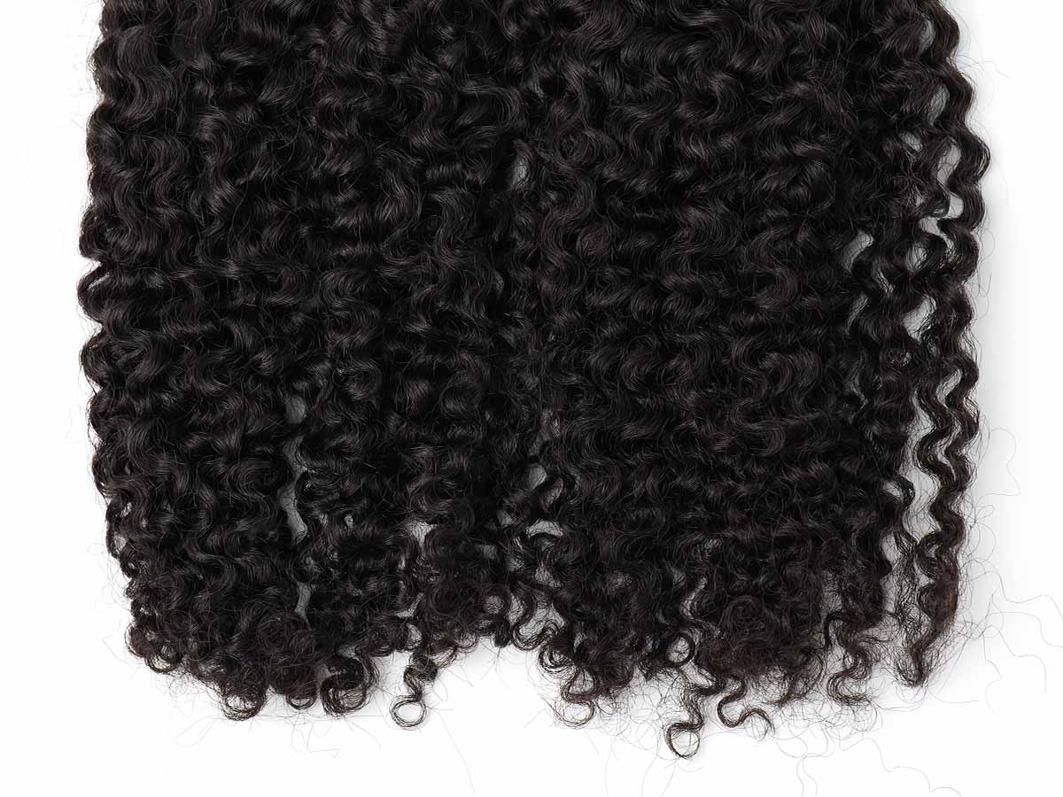 Close-up shot of the ends of jerry curl tape-in extensions, showing curl density and finish.
