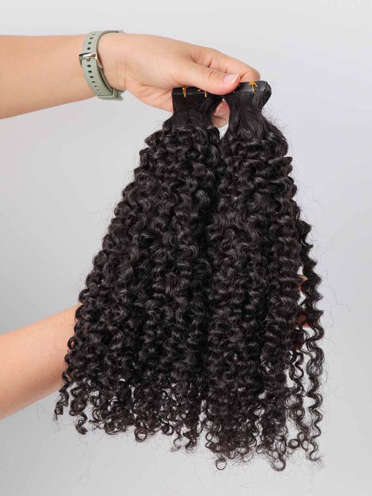 Jerry curl tape-in extensions held straight in hand, showing full length and texture from top to ends.