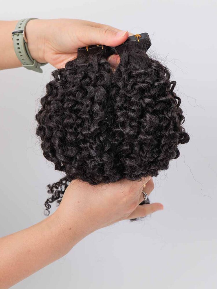 Black Line jerry curl tape-in extensions held with a curved shape, highlighting the tight curl texture.