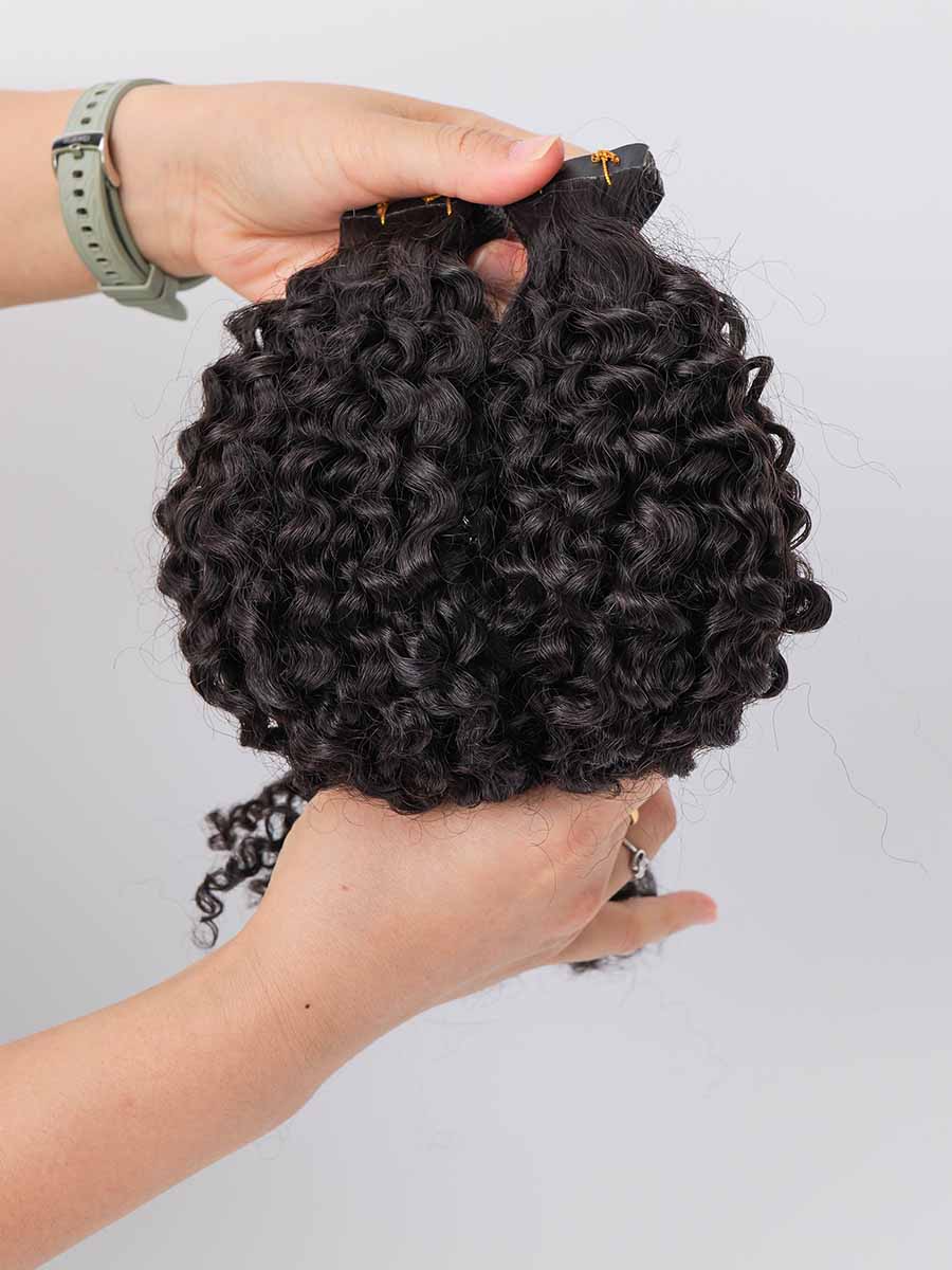 Black Line jerry curl tape-in extensions held with a curved shape, highlighting the tight curl texture.