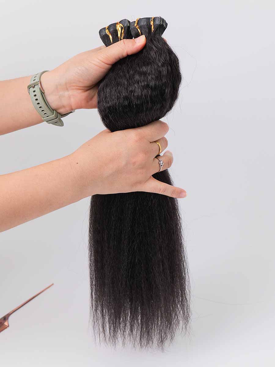 black line kinky straight tape-in extensions held in hand with slight volume